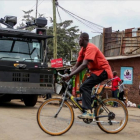Un ciclista pasa por delante de un vehículo antidisturbios en las chabolas de Kibera, en Nairobi, el 7 de agosto.