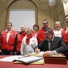 El presidente comarcal, Acacio Díaz, acompañado de varios voluntarios, firma en el libro de honor tras recibir el galardón. JESÚS