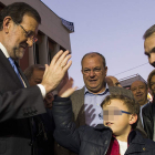 El presidente del Gobierno y del PP saluda a un niño antes del inicio de un acto en Badajoz.