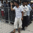 Refugiados e inmigrantes esperan junto a un autobús mientras la policía continúa con el desalojo del campo en Grecia.  NIKOS ARVANITIDIS