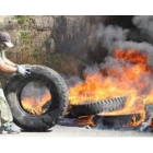 Un manifestante desplaza una rueda para abastecer de material inflamable la barricada situada a la e