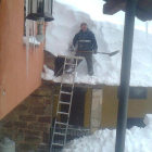 Un hombre espala nieve de un tejado en Genestosa de Babia