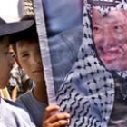 Un niño palestino pasea una bandera con el rostro de Yaser Arafat