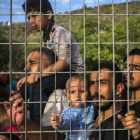 Refugiados e inmigrantes esperan tras una verja, en un campo de fútbol, a poder ser registrados, en Mitilene, este martes.