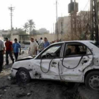 Dos hombres observan los daños de un coche junto a la catedral católica de Sayidat al-Nejat