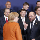 El presidente del Parlamento Europeo, Martin Schulz, se dirige a la cancillera alemana, Angela Merkel, ante el presidente francés, François Hollande (de espaldas), durante la foto de familia, el jueves en Bruselas.
