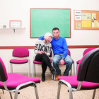 Juan abraza a Aroa en la sala de terapia, donde los usuarios y familiares comparten sus experiencia. Detrás se lee: «También se vive sin alcohol».