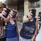 Unas adolescentes muestran sus teléfonos móviles a la puerta de su instituto en Barcelona.