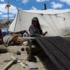 Dos mujeres tejen en un campamento nómada.