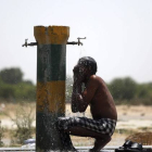 Un trabajador indio se refresca bajo un grifo una calurosa tarde en Amritsar (India).