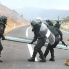 Agentes del GRS retiran una valla de la A-6 tras ser arrancada por los mineros.