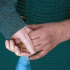 Un anciano con alzhéimer coge la mano de la persona que lo asiste.