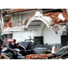 Un motorista pasa junto a una casa reducida a escombros tras el potente terremoto que arrasó Indones