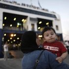 Una refugiada siria sostiene a un bebé antes de abordar un barco hacia El Pireo.