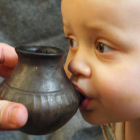 Un niño bebe agua en un biberón de arcilla como los usados en el Neolítico. NATURE