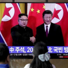 Unos transeúntes observan un programa de TV en el que aparecen el presidente chino Xi Jinping saludando al líder norcoreano Kim Jong-un en Pionyang.