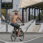 Un ciclista circula junto a un termómetro a 44 grados en Sevilla.