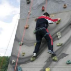 Un niño practica escalada en un rocódromo, agarrado por una cuerda para garantizar su seguridad