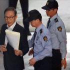 Imagen de archivo del expresidente surcoreano Lee Myung-bak mientras es escoltado por policías en la sala de un tribunal en Seúl.