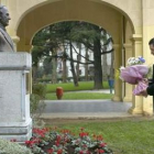 Una persona deposita flores ante el busto dedicado al religioso