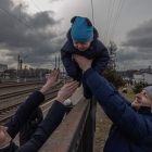 Oleg pasa por encima de una valla en Irpín a su hijo Maksim y se lo entrega a su mujer Ana antes de la llegada de un tren de evacuación a la ciudad de Kiev para salir del país. ROMAN PILIPEY