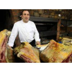 José Gordón, en el asador de su establecimiento, junto a varios costillares de los que ofrece.