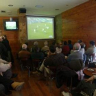 Un grupo de aficionados sigue un partido de fútbol en un bar.