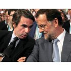 El expresidente del Gobierno, José María Aznar, conversa con el candidato del PP, Mariano Rajoy, durante la convención.