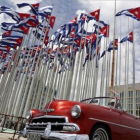 Un coche clásico americano pasa al lado de la embajada estadounidense en La Habana, donde ondean decenas de banderas de Cuba.