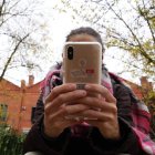 Una joven utiliza su teléfono móvil junta a un instituto de la capital vallisoletana. RUBÉN CACHO