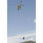 Momento en el que dos bomberos participantes en el simulacro son izados por el helicóptero