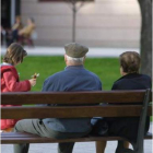 Unos ancianos sentados en un banco junto a su nieta.