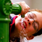 Imagen de un niño bebiendo agua en una fuente, debido al calor del verano