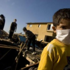 Un niño ayuda a su familia a recoger escombros.