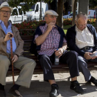 Tres jubilados descansan en un banco de un parque en Valencia.