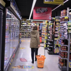 Una clienta deambula entre los estantes llenos de productos de un supermercado .