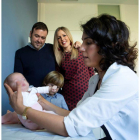 La doctora Georgia Sarquella con la bebé y la familia de fondo. ENRIC FONTCUBERTA