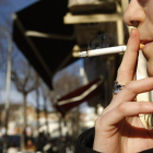 Una mujer fuma en la calle.