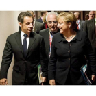 Sarkozy y la canciller alemana Ángela Merkel charlan mientras se dirigen a la cena de trabajo de ayer en Bruselas.