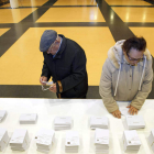 Dos ciudadanos escogen sus papeletas en el colegio electoral.