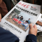Un hombre lee un periódico donde aparece en portada el presidente Xi en una plantación de árboles, el 6 de abril, en Pekín.