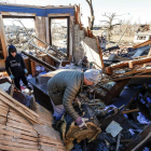 Un hombre y su hijo rebuscan entre los restos de su casa, arrasada por uno de los tornados. TANNEN MAURY