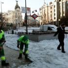 Dos operarios limpian las aceras de la calle Alcalá en Madrid mientras pasa una peatona. MARISCAL