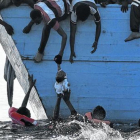 Unos inmigrantes tratan de sacar a un niño del mar frente a las costas de Libia, en una foto de archivo.