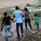 Una familia de inmigrantes cruzan de manera ilegal la frontera entre México y los EEUU. / MARIO TAMA (AFP)