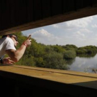 Un joven contempla la laguna desde la caseta de observación de aves.