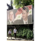 Dos hombres pasan ante un cartel con la imagen del presidente sirio
