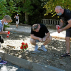 Tres personas encienden velas junto a un ramo de flores en el lugar donde murió la mujer. PABLO MARTÍN