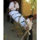 Agentes de los servicios funerarios trasladan el cadáver de la degollada