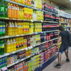 Un joven, ante la estantería de refrescos de cola, en un supermercado